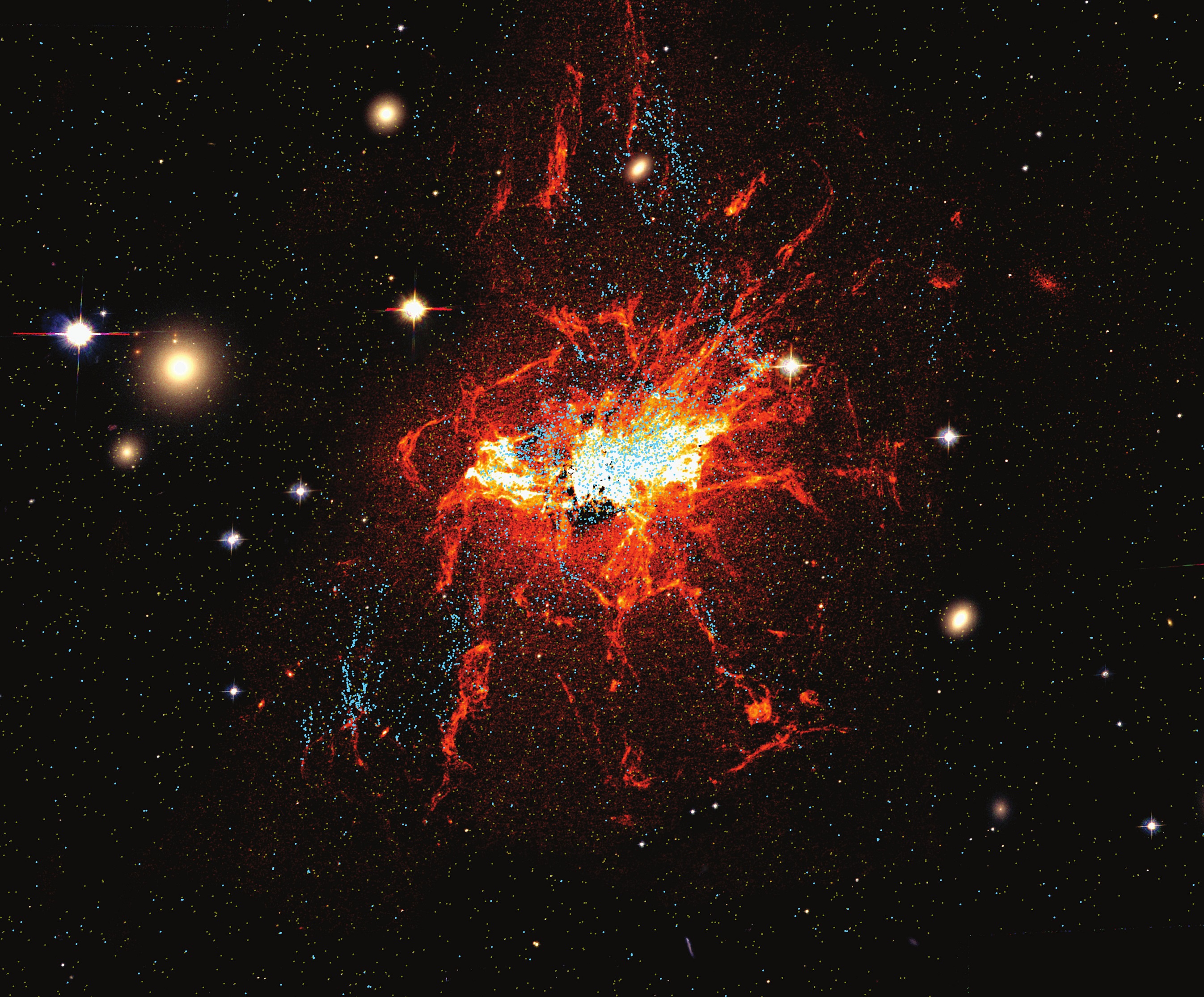 Imagen del telescopio espacial Hubble, en el que se ven los cúmulos globulares jóvenes en azul y los filamentos de gas frío en rojo.