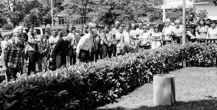 Dantzariek agur egiten diote lorategi batean dagoen omenezko plakari jendearen aurrean