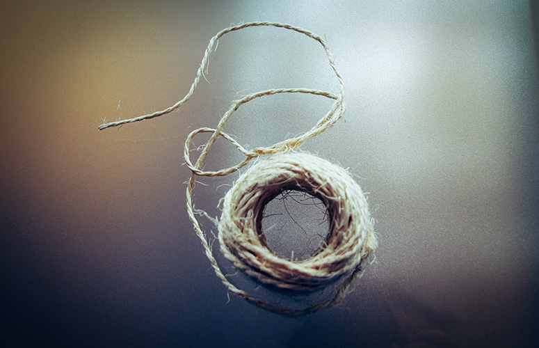 Hondo zehaztugabe baten aurrean, bere hariletik askatzear dagoen kordel burdin eta biluzi bat flotatzen dagoela dirudi.