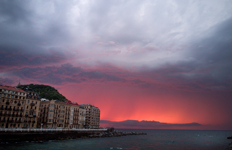 Pasealeku batetik ibai baten bokalea ikusten dugu. Ezkerrean hiria dugu, sei solairu inguruko garai ezberdinetako eraikuntzekin, bata bestearekin pilatuta, zuriz hesitutako itsas-pasealeku batez inguratuta. Atzean, muino berde bat. Bokala amaituta, itsasoa eta zeruertza zabaltzen dira. Zerua hodeitsua eta etereoa da, tonu arrosa eta laranjetan.