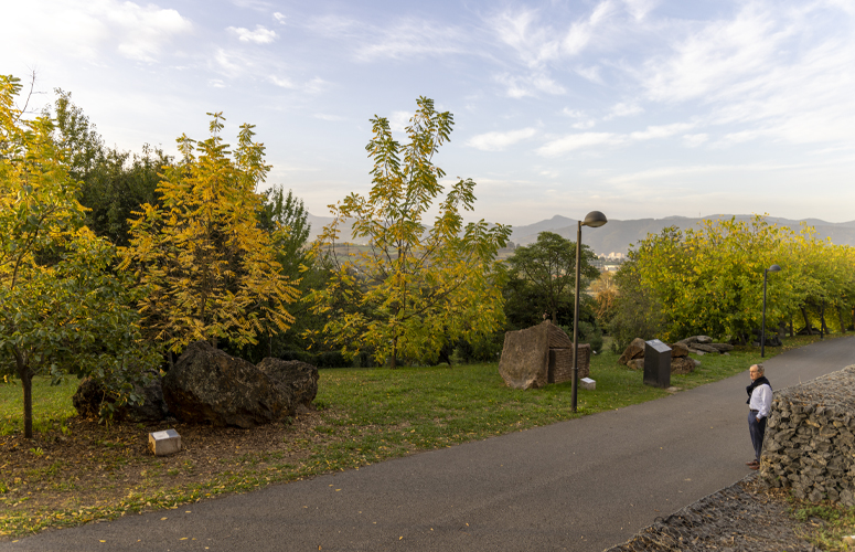 José Mª Gorostiagaren txoko gogokoenaren ikuspegi orokorra, Leioako Arboretumeko pasealeku nagusian. Bertan, burdinazko mea (ezkerra) eta Ereñoko marmol gorria (eskuina) ikus daitezke, intxaurrondo beltzaren zenbait alerekin batera.