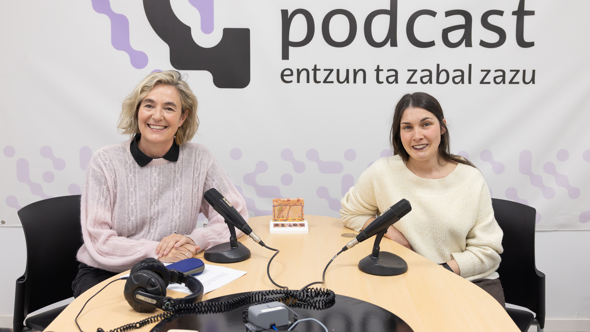 Tania Arriaga y Cristina Penas Lago con la maqueta de la piel representando los distintos estadios del melanoma, en el laboratorio de radio de la Facultad de Ciencias Sociales y de la Comunicación.